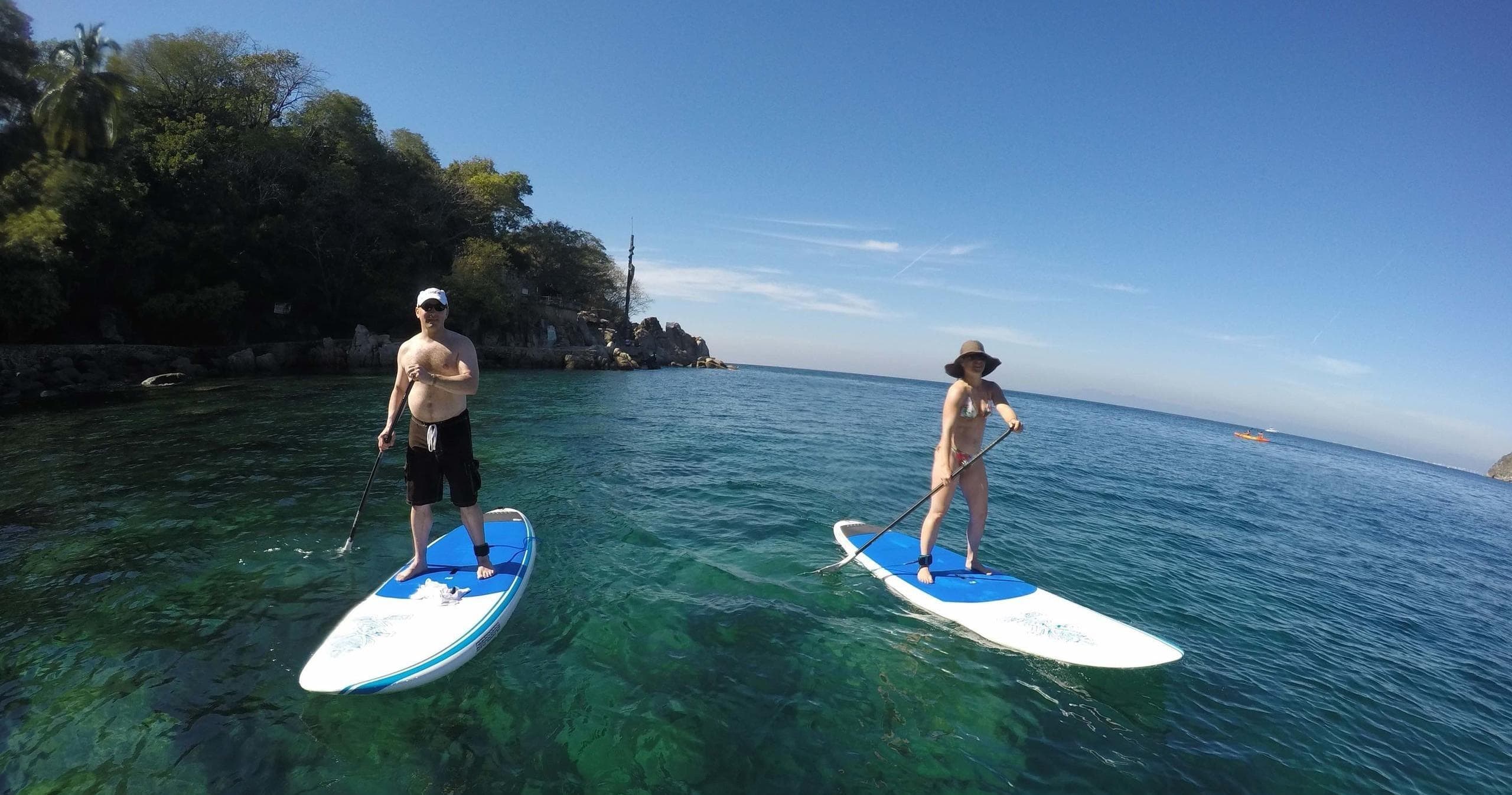 Two stand-up paddleboarders on clear tropical water