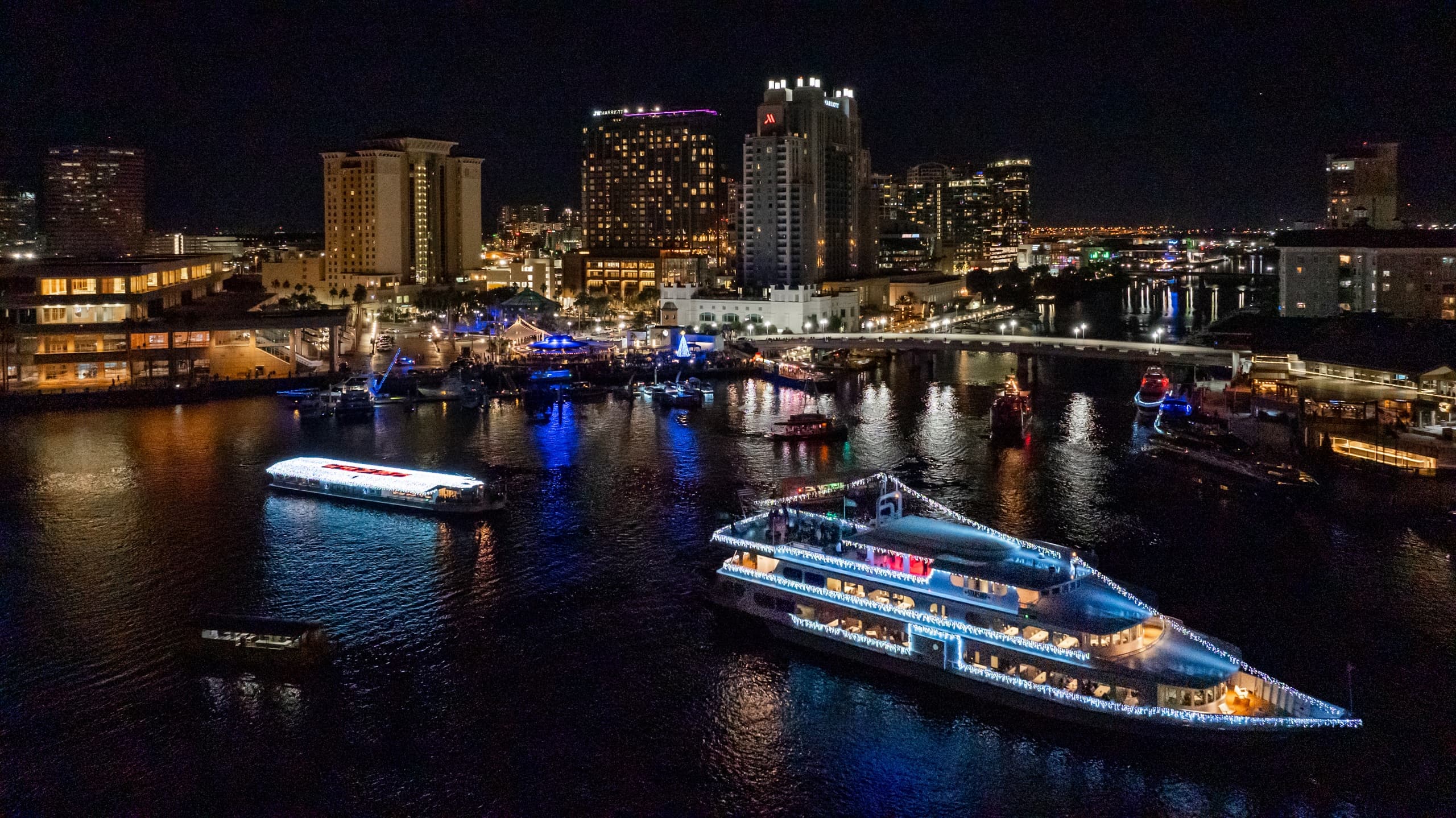 Nighttime harbor with illuminated sightseeing yachts and skyline