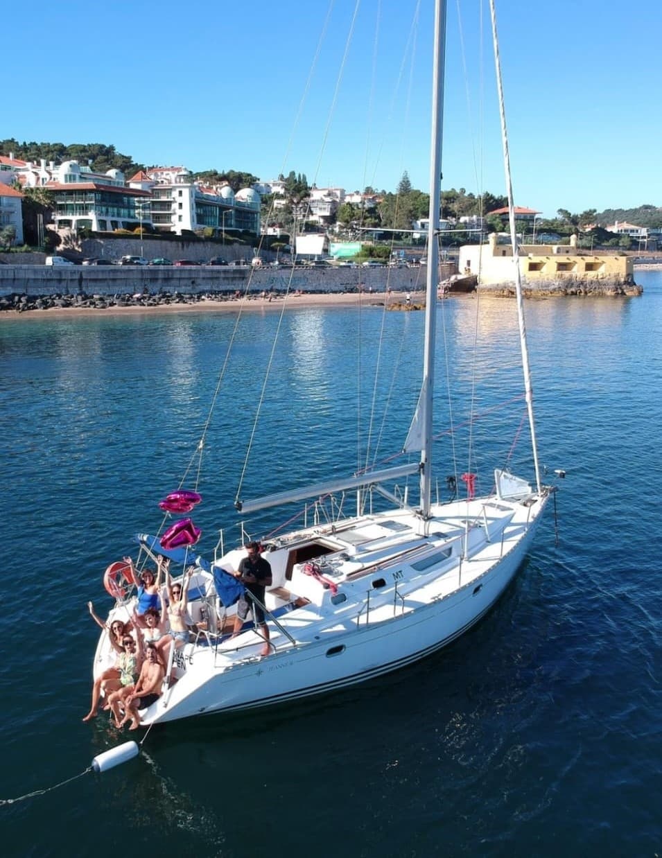 White sailboat anchored in coastal harbor under clear sky