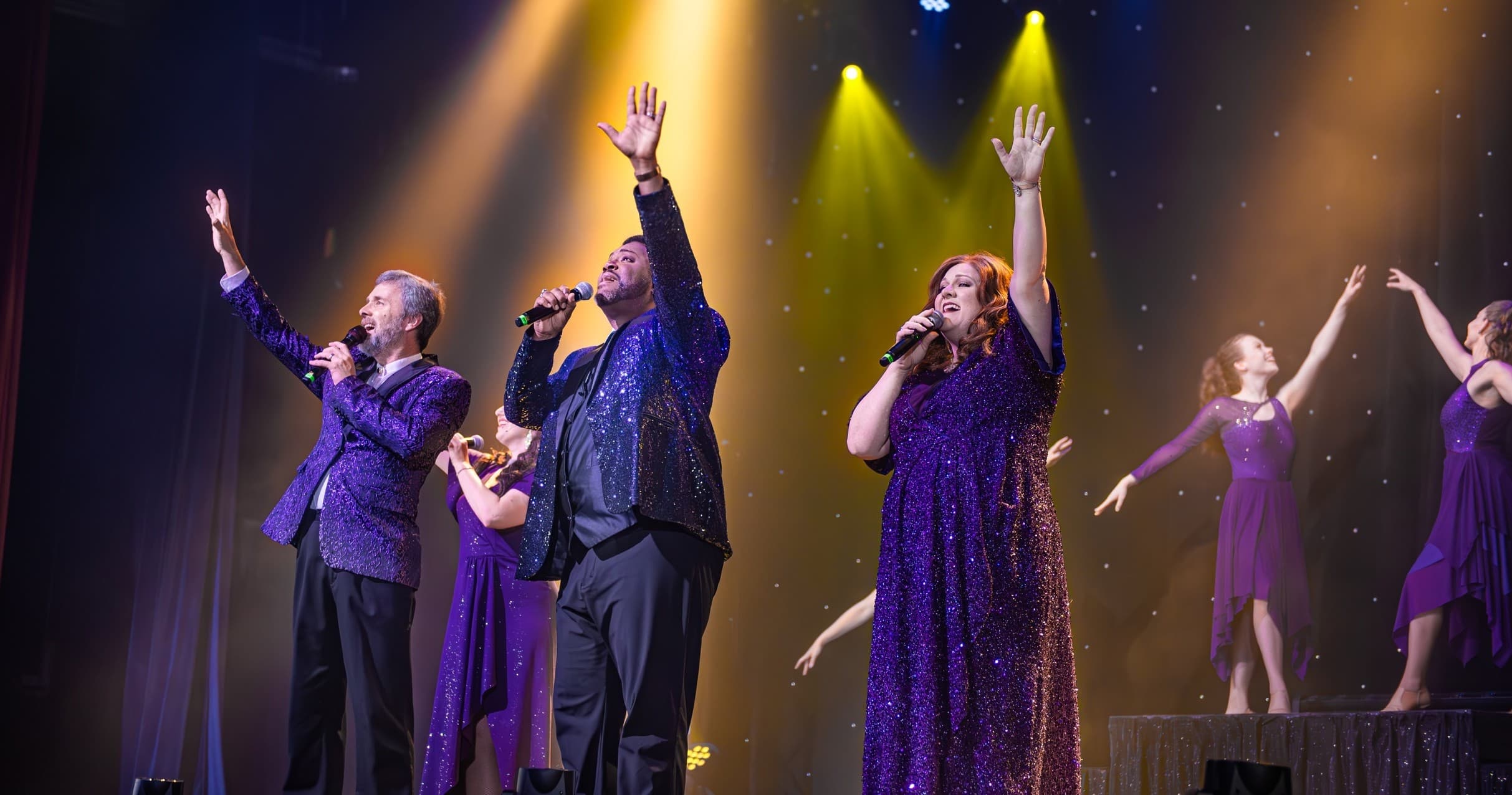 Vocal quartet singing live under dramatic stage lights in theater