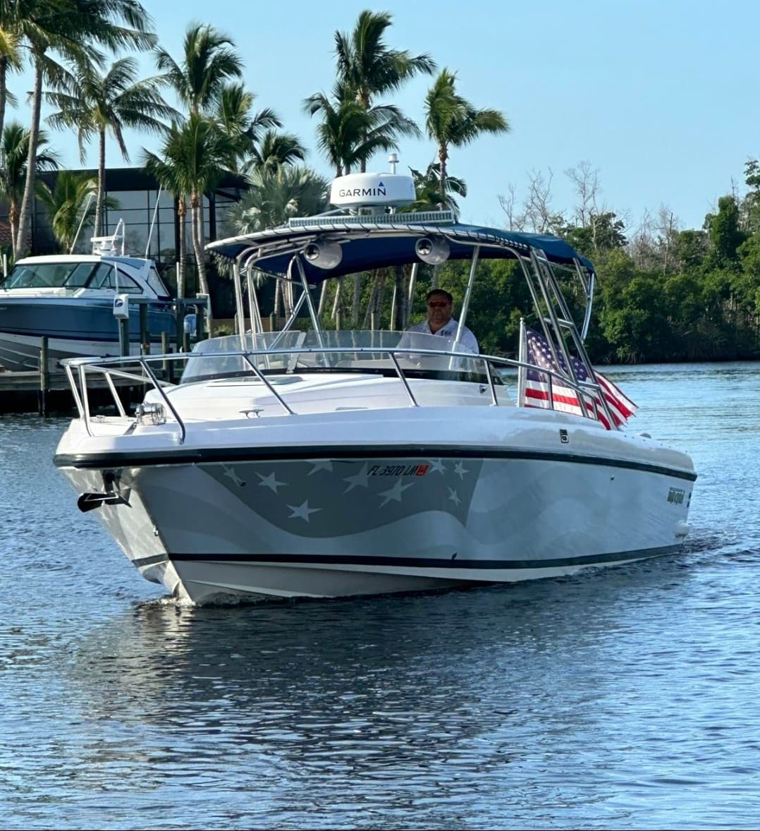 Small powerboat near mangroves and palm-lined shore on river