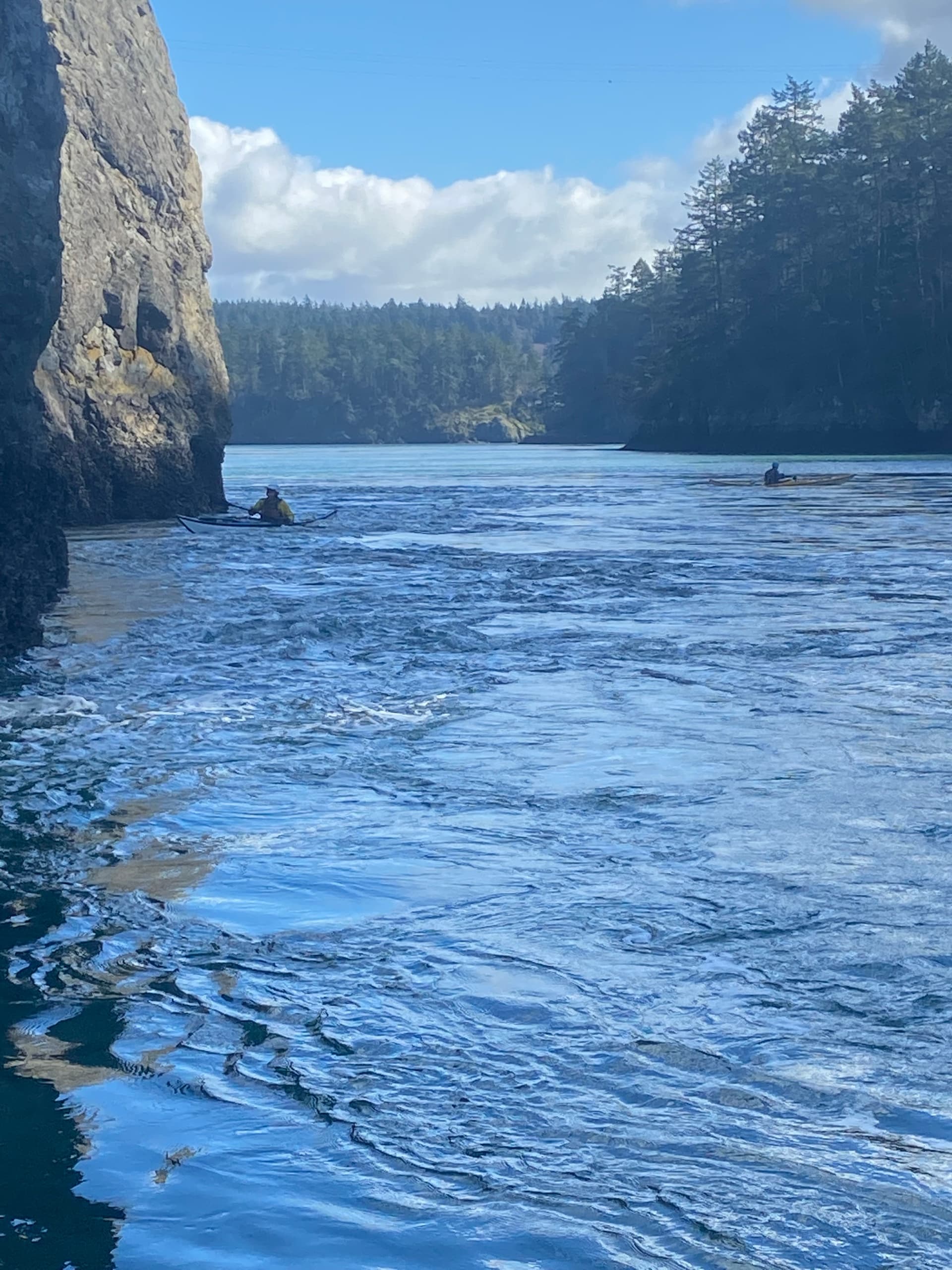 Kayaker paddling through narrow sea channel between rocky cliffs