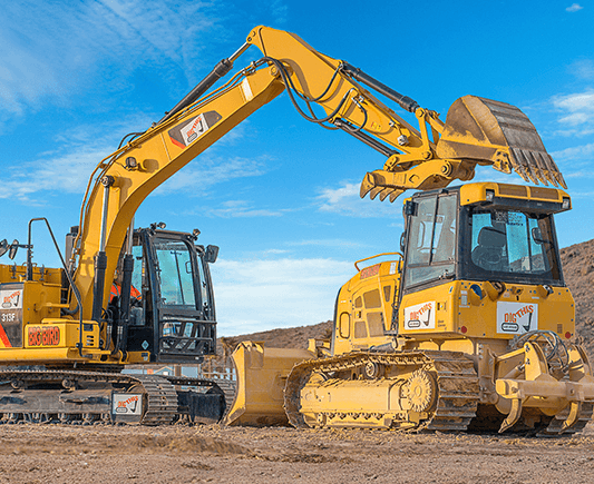 Two excavators loading and lifting dirt on sunny Nevada worksite