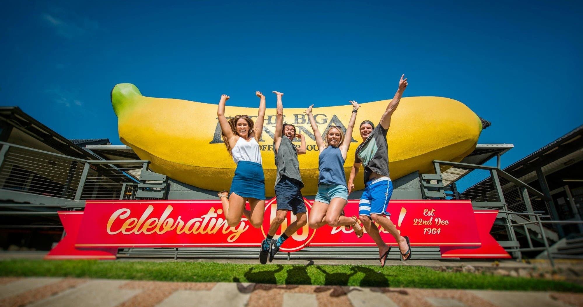 People jumping in front of giant Big Banana landmark outdoors