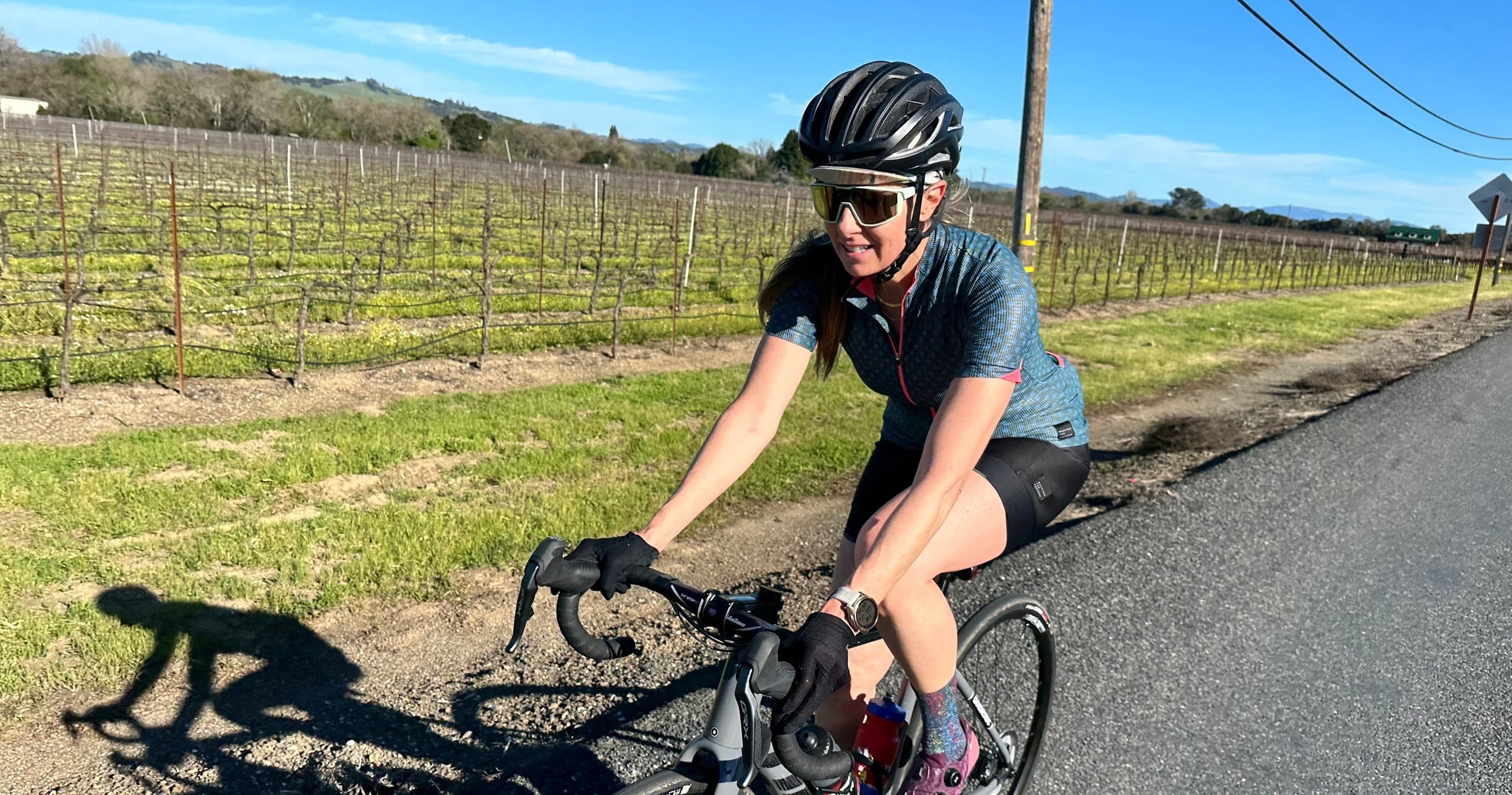 Road cyclist riding past vineyards on scenic country road ride