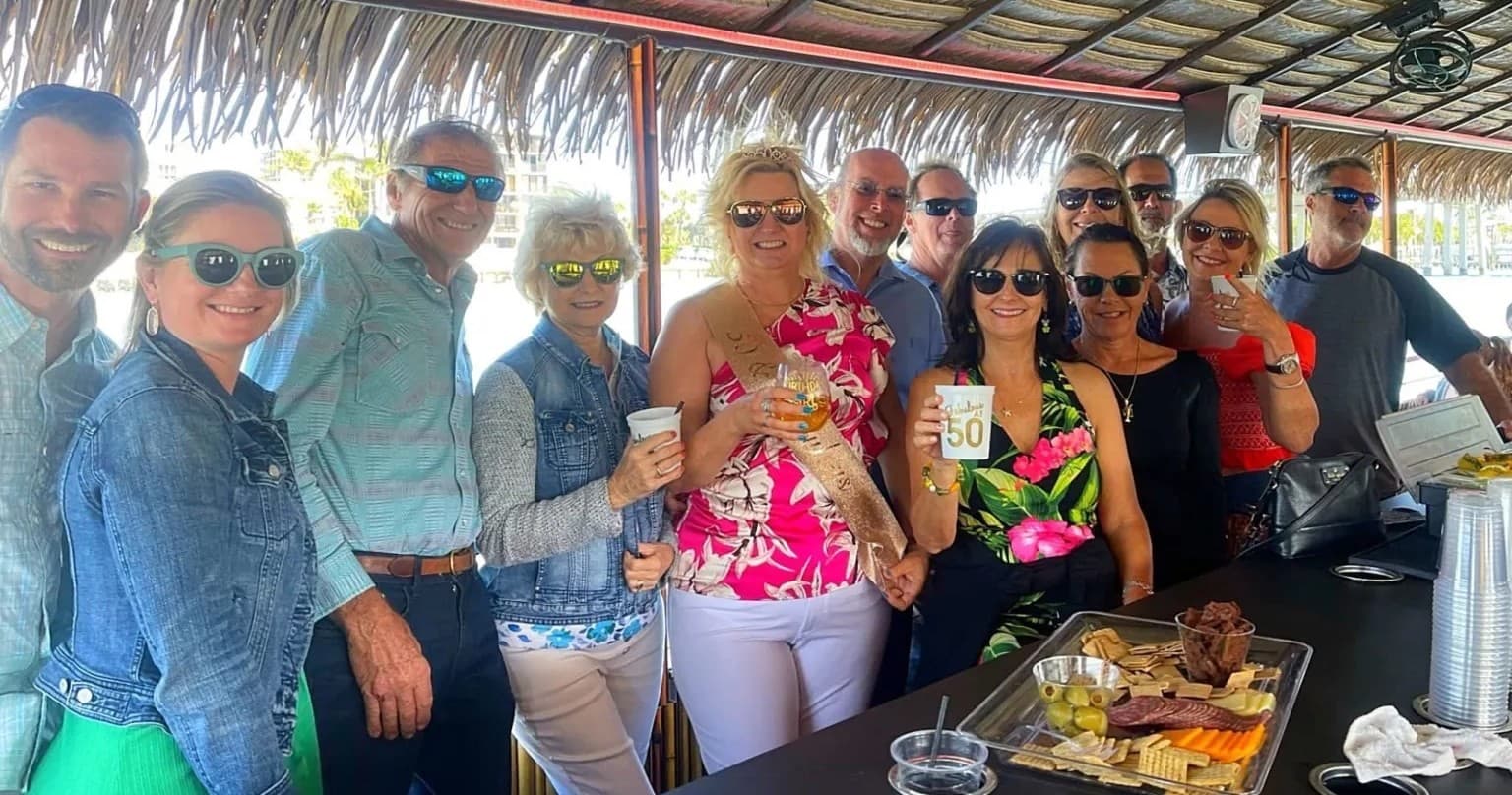 Large group socializing on covered party boat with snacks