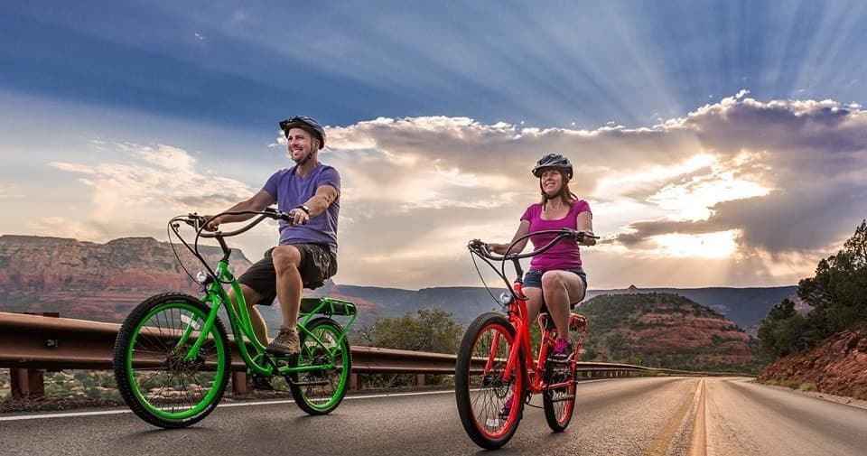 Two cyclists on colorful e-bikes riding scenic desert road
