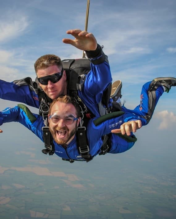 Tandem skydiving instructor and student smiling midair