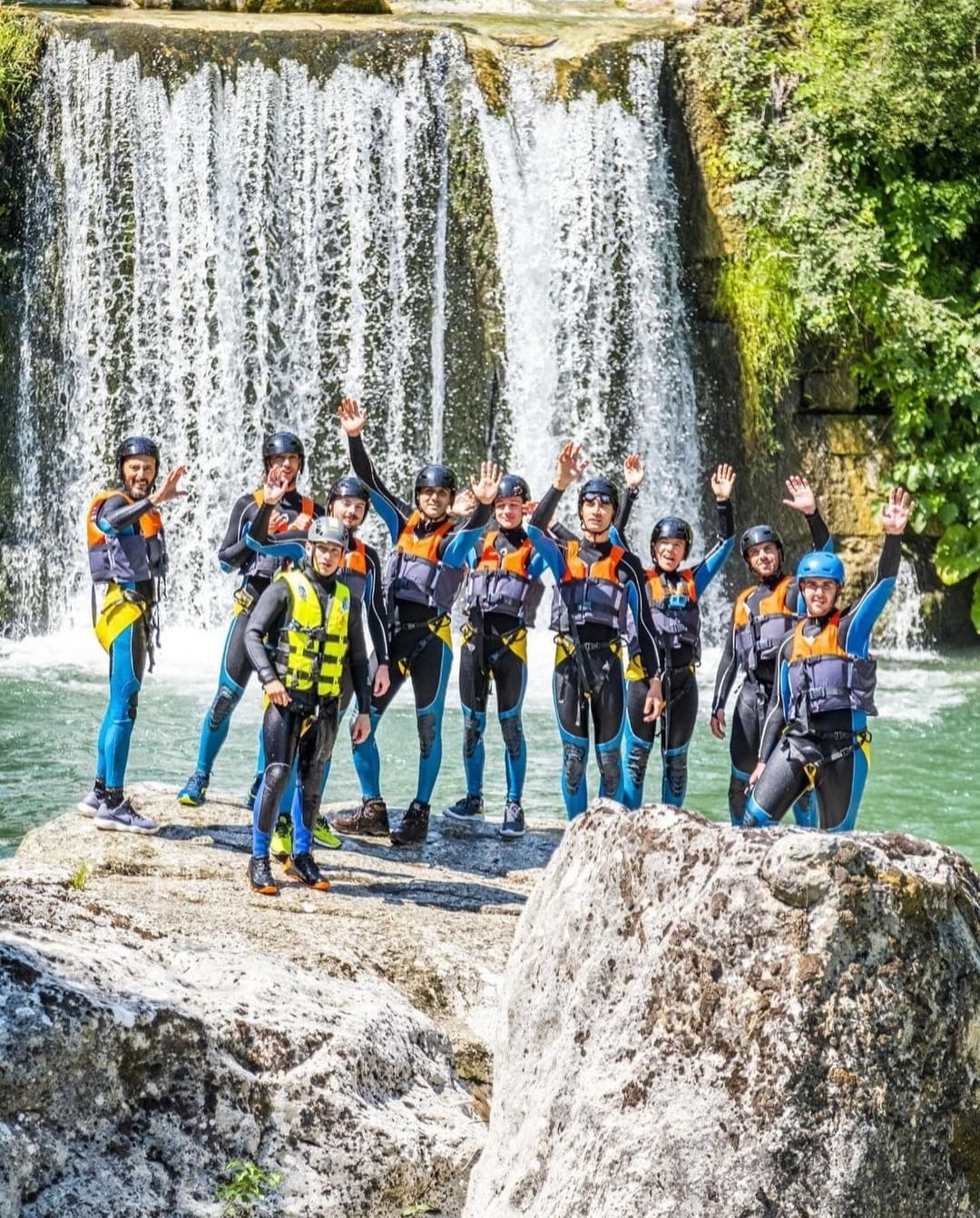 Canyoning group posing by waterfall on river gorge adventure
