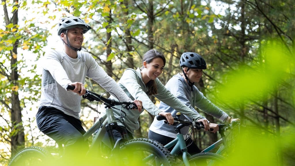 Cyclists mountain biking through leafy forest trail in autumn