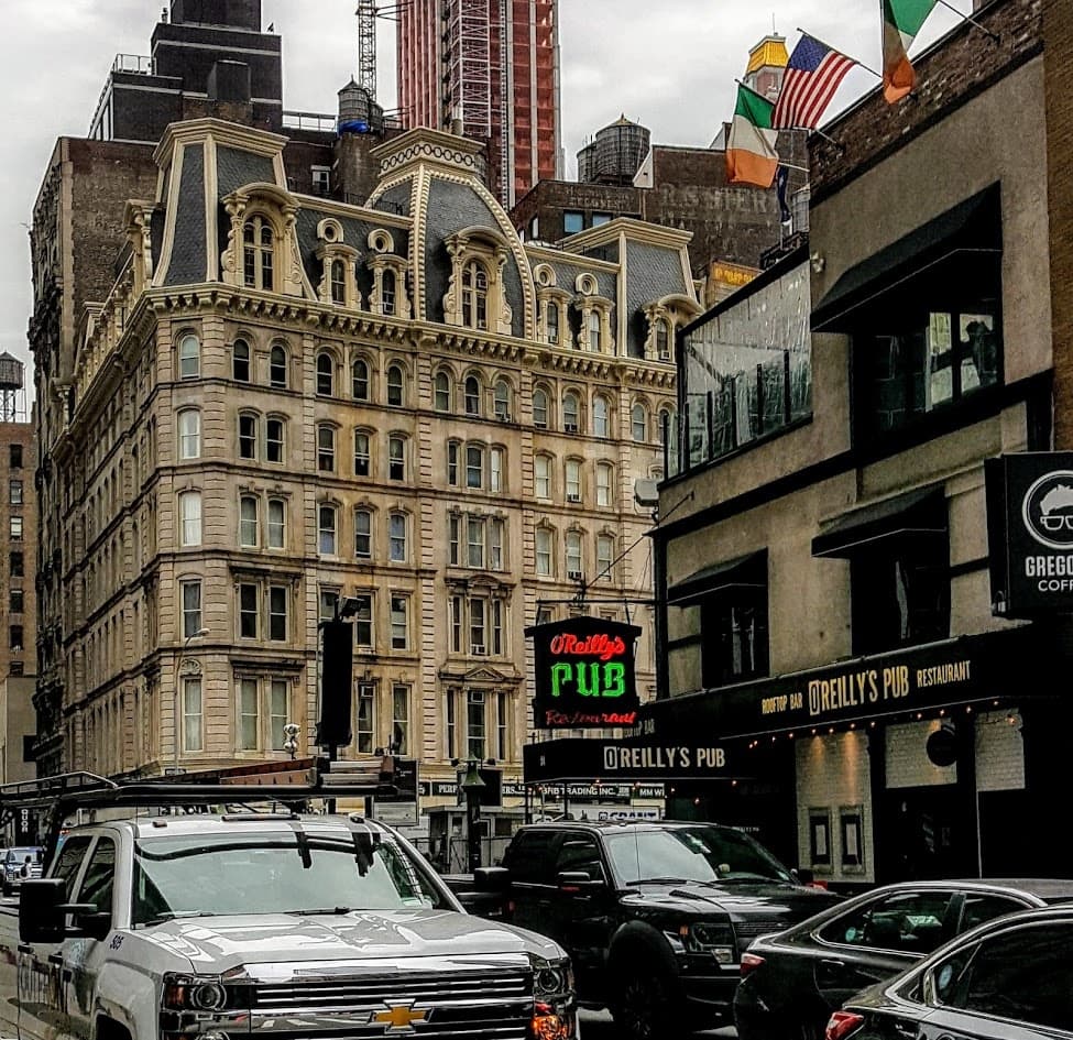 Historic Manhattan streetscape with parked cars and pubs
