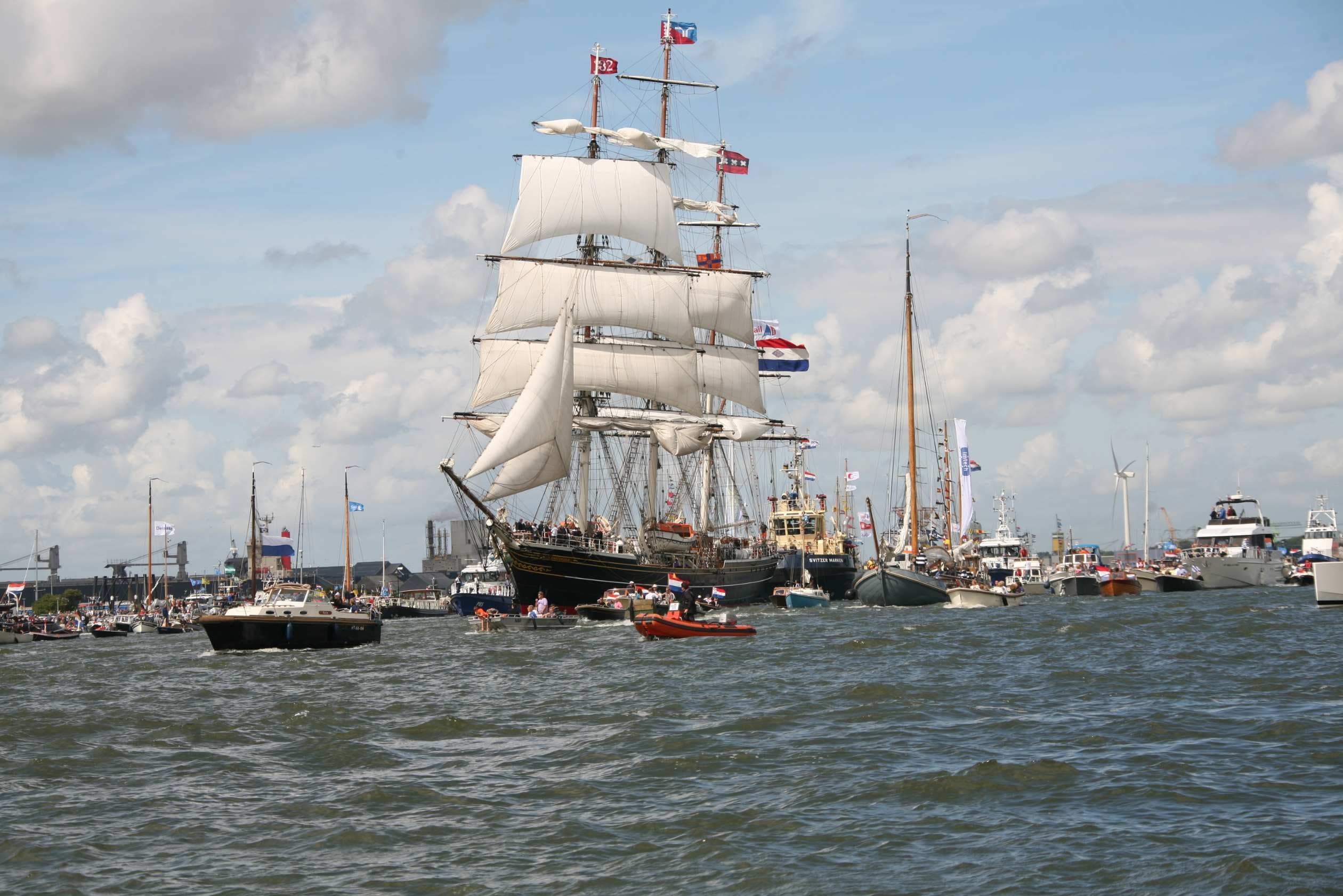 Tall sailing ship under cloudy sky in harbor maritime festival
