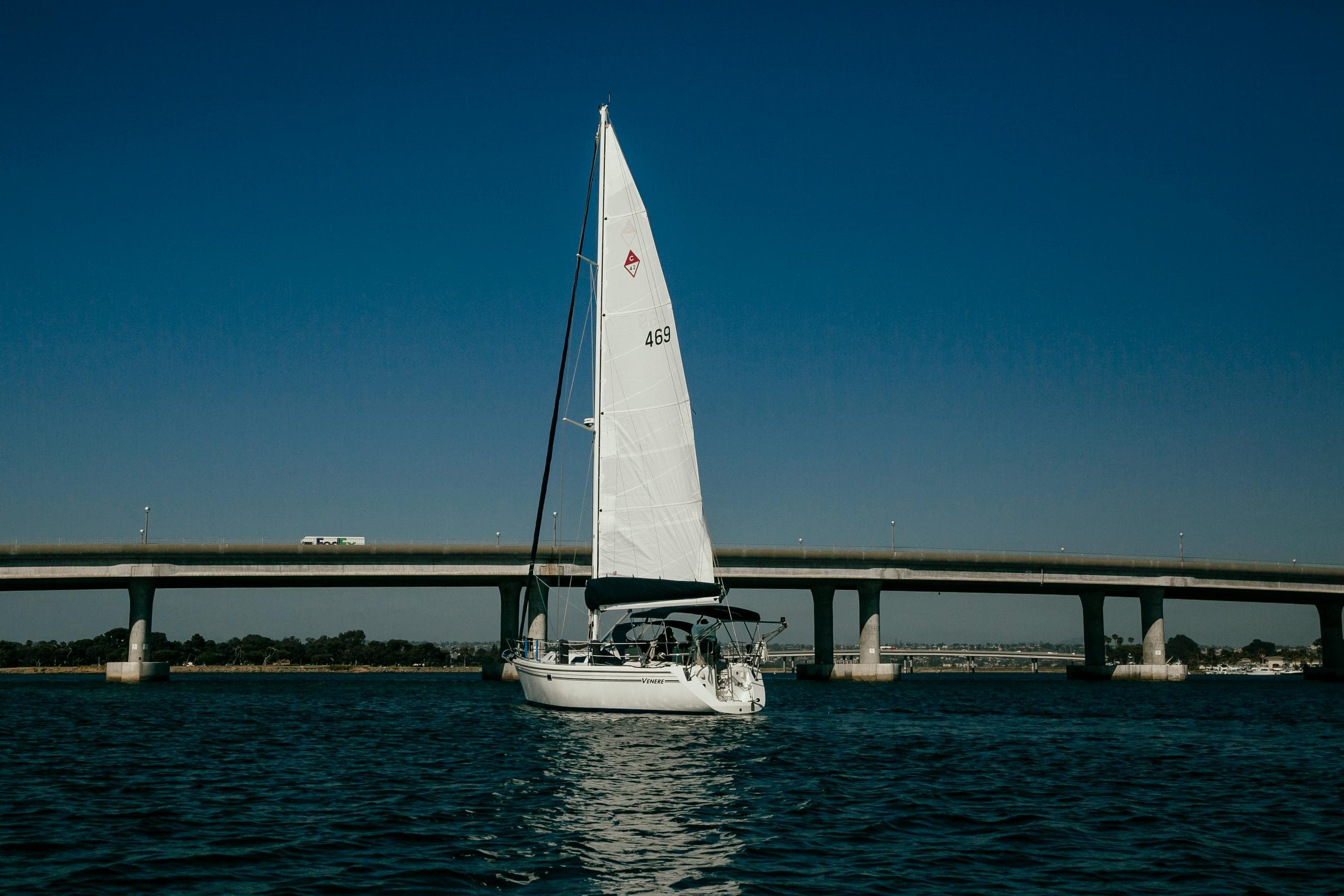 Sailboat cruising under bridge on calm harbor waters