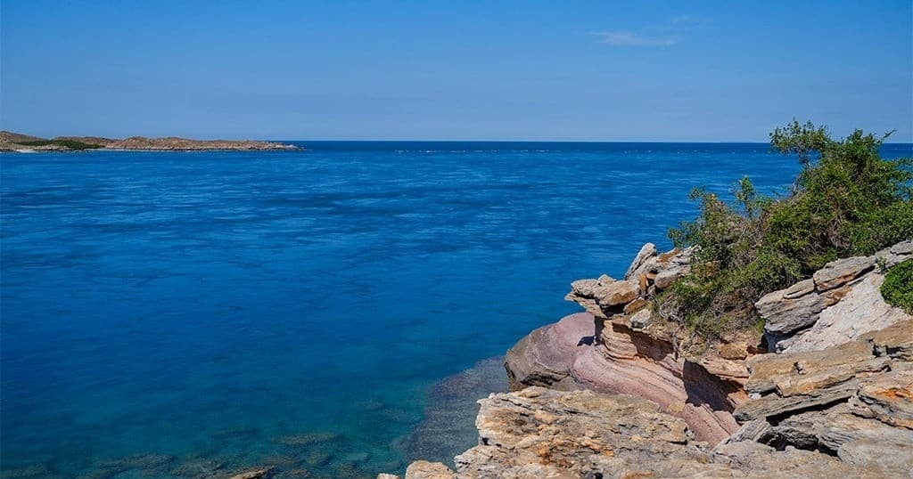 Coastal hiking on rocky shoreline with clear blue sea views