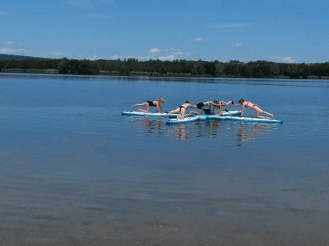 Friends forming SUP float on calm lake, recreational tour