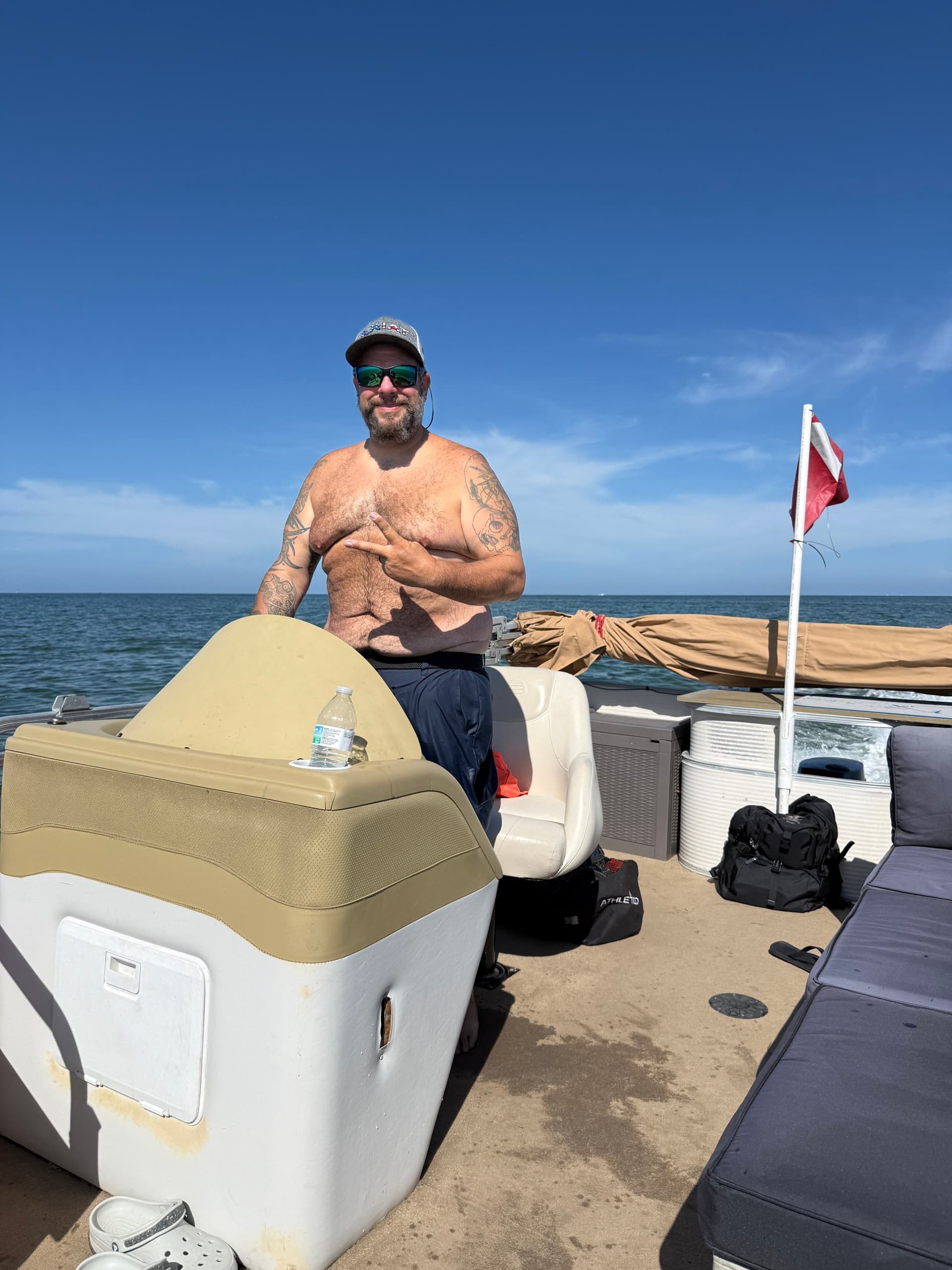 Captain steering pontoon boat on open ocean under sunny sky