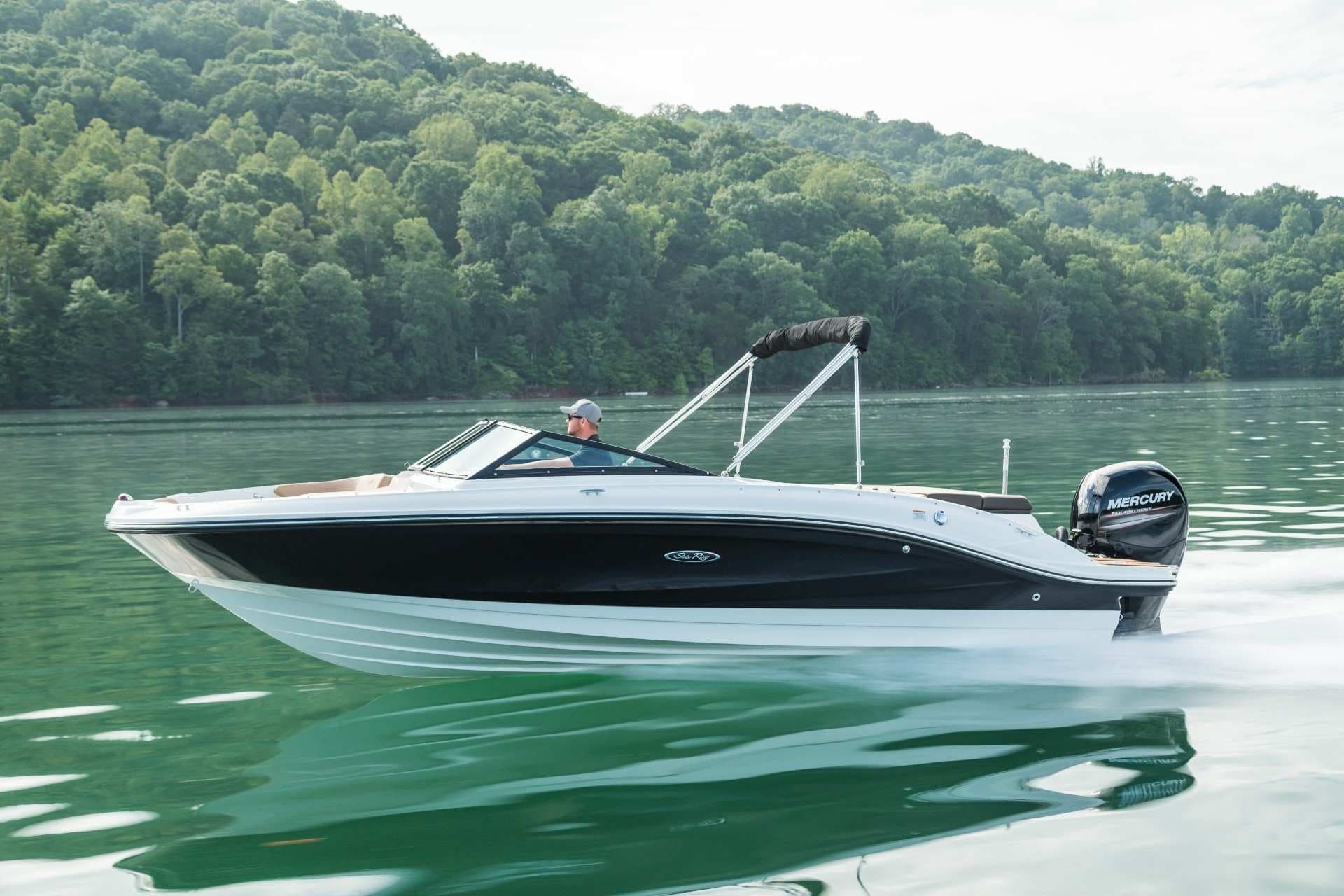 Motorboat cruising on green lake with forested hills backdrop