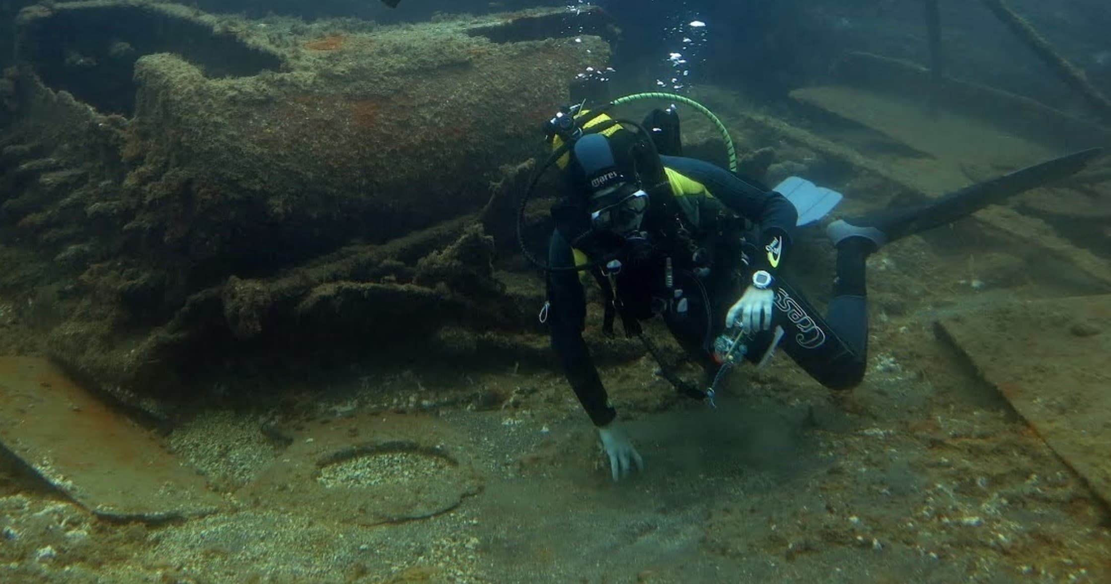 Scuba diver exploring shallow coastal wreck on rocky seabed