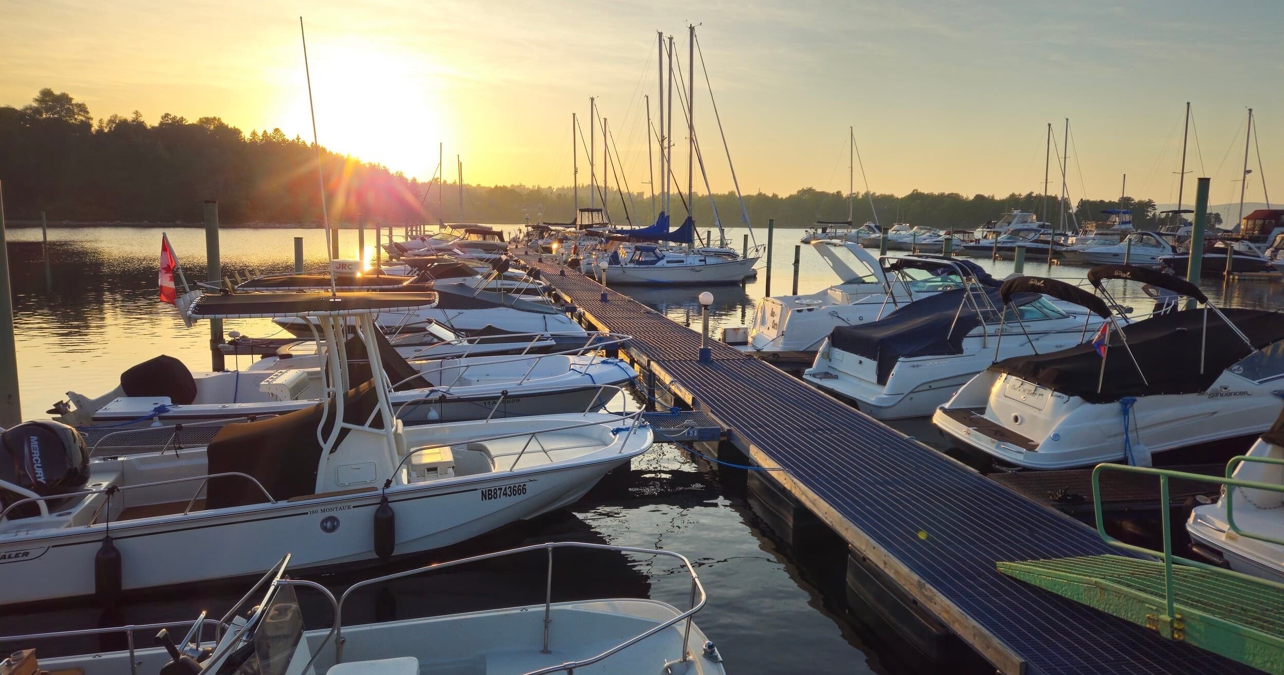 Sunrise marina with moored boats and wooden dock at golden hour