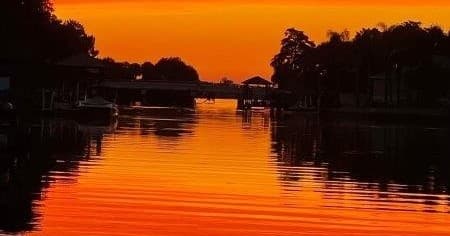 Orange sunset over coastal canal with reflective water and docks