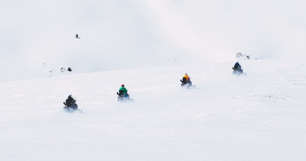 Four-wheelers parked at sunset on rolling hills near lake