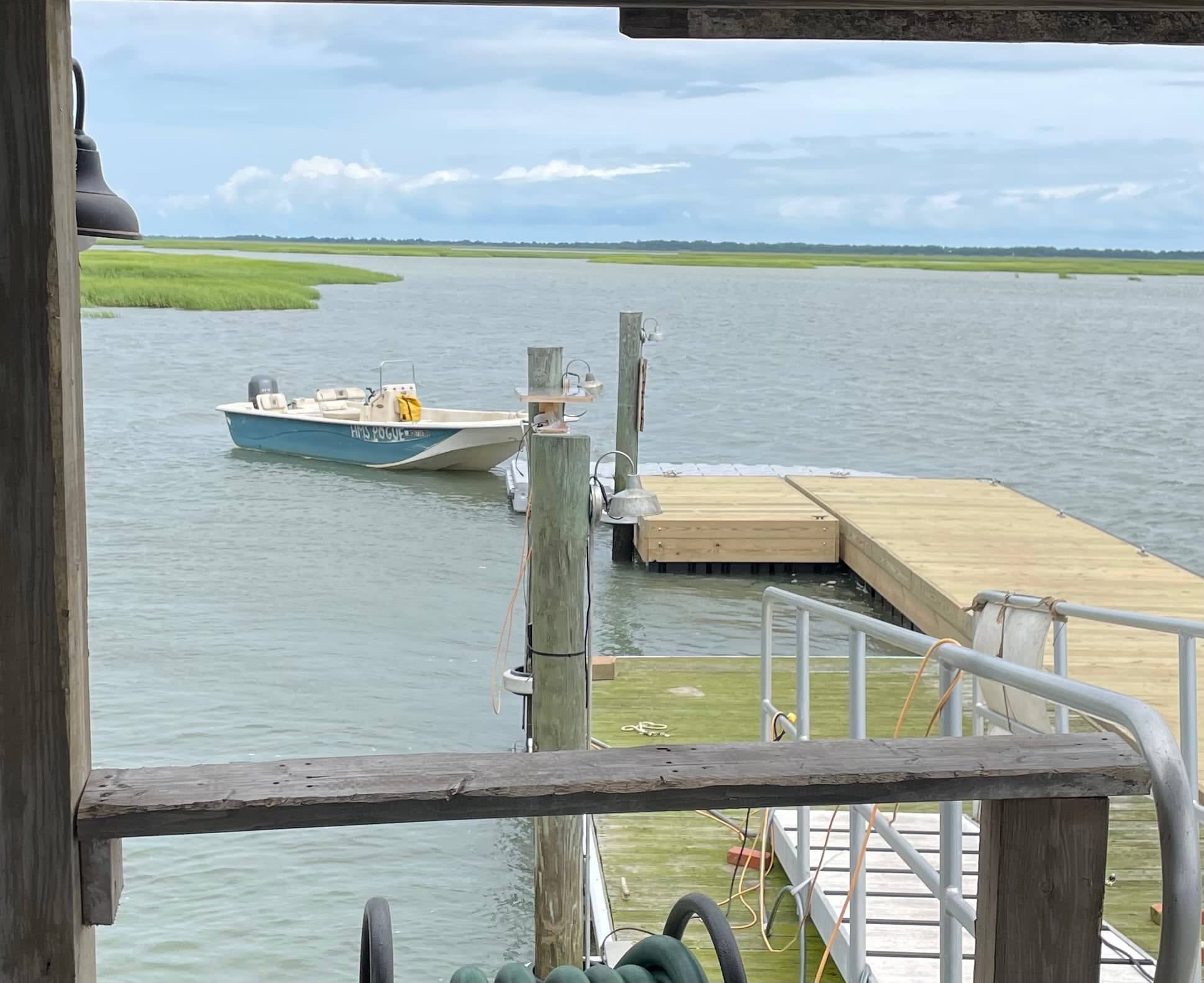 Scenic dock view with small skiff moored at tidal creek pier