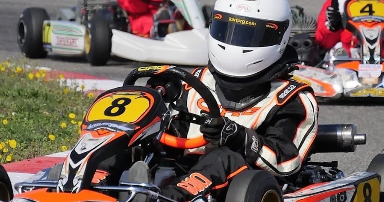 Competitive go-kart racer in helmet speeding on outdoor track