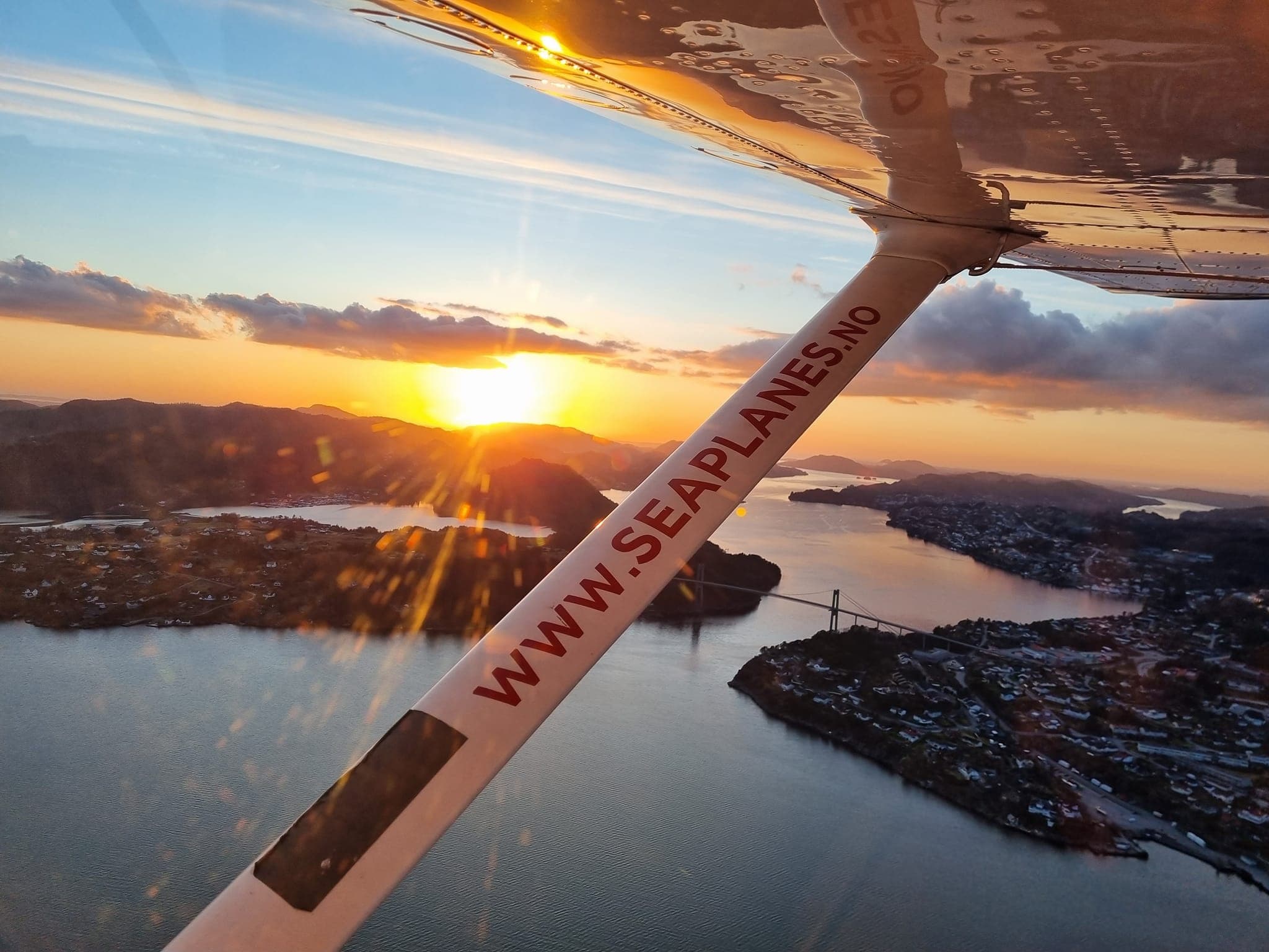 Sunset seaplane flight over Norwegian fjords from wing window