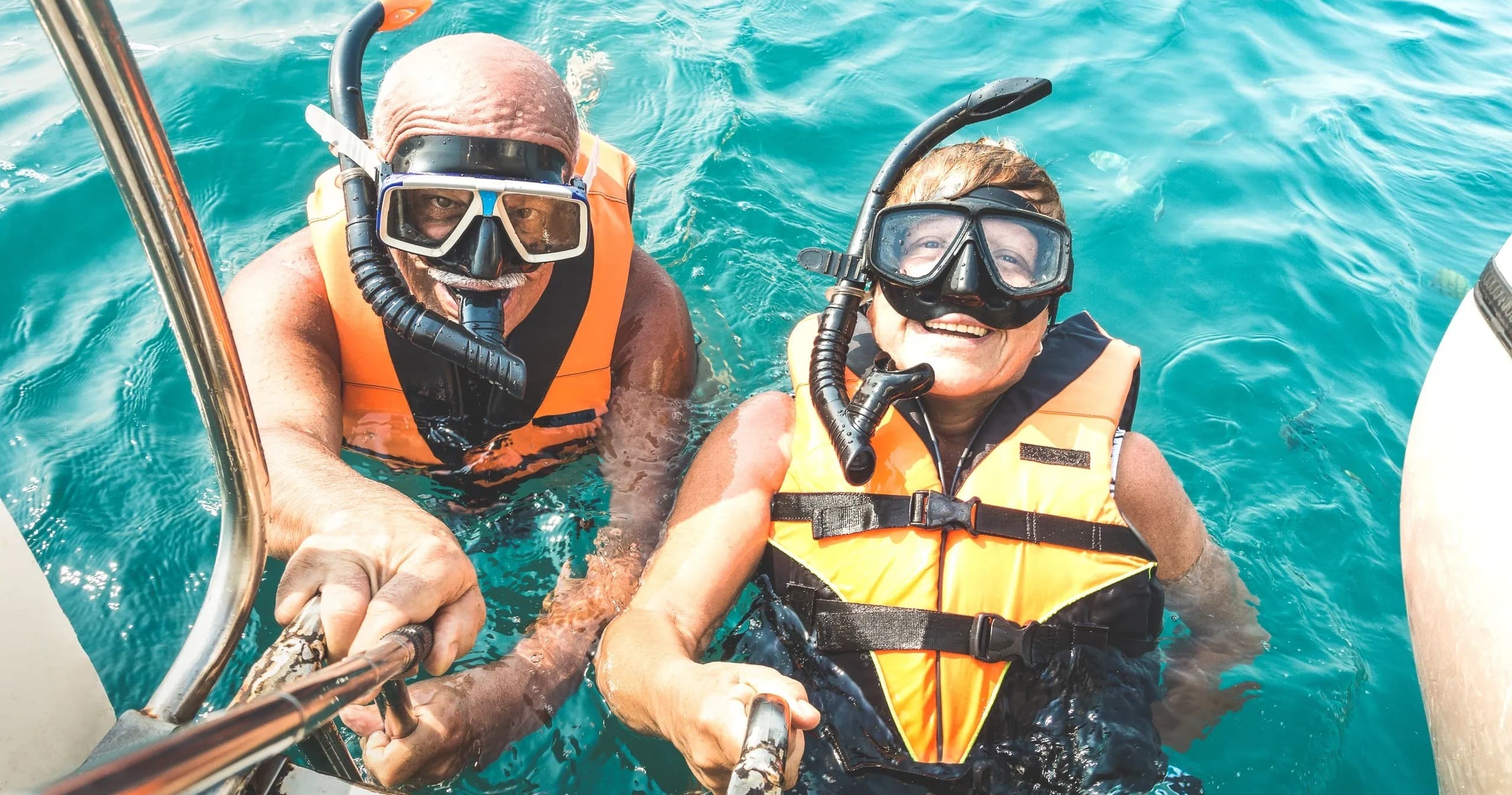 Couple in snorkel gear taking boat selfie in turquoise sea