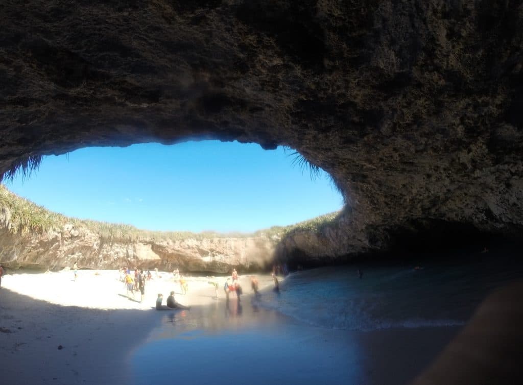 Ocean cave opening revealing sandy beach and turquoise water shore