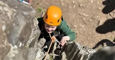Young climber ascending crag on outdoor rock face in Scotland