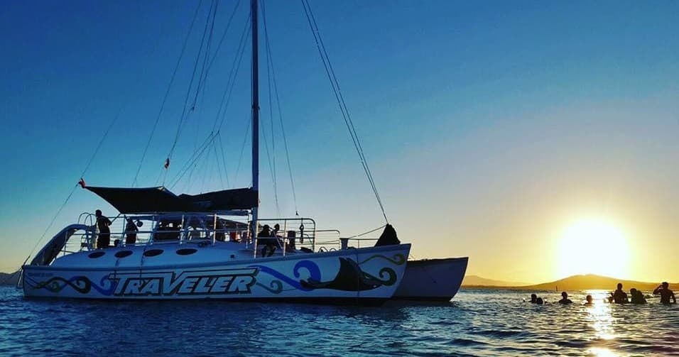 Sunset catamaran silhouette with calm sea and golden sky