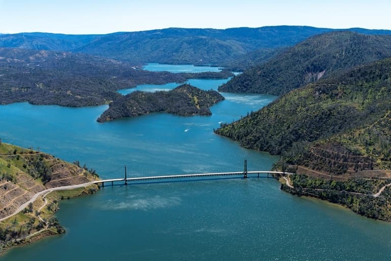 Aerial view of reservoir and bridge over blue lake, scenic flight