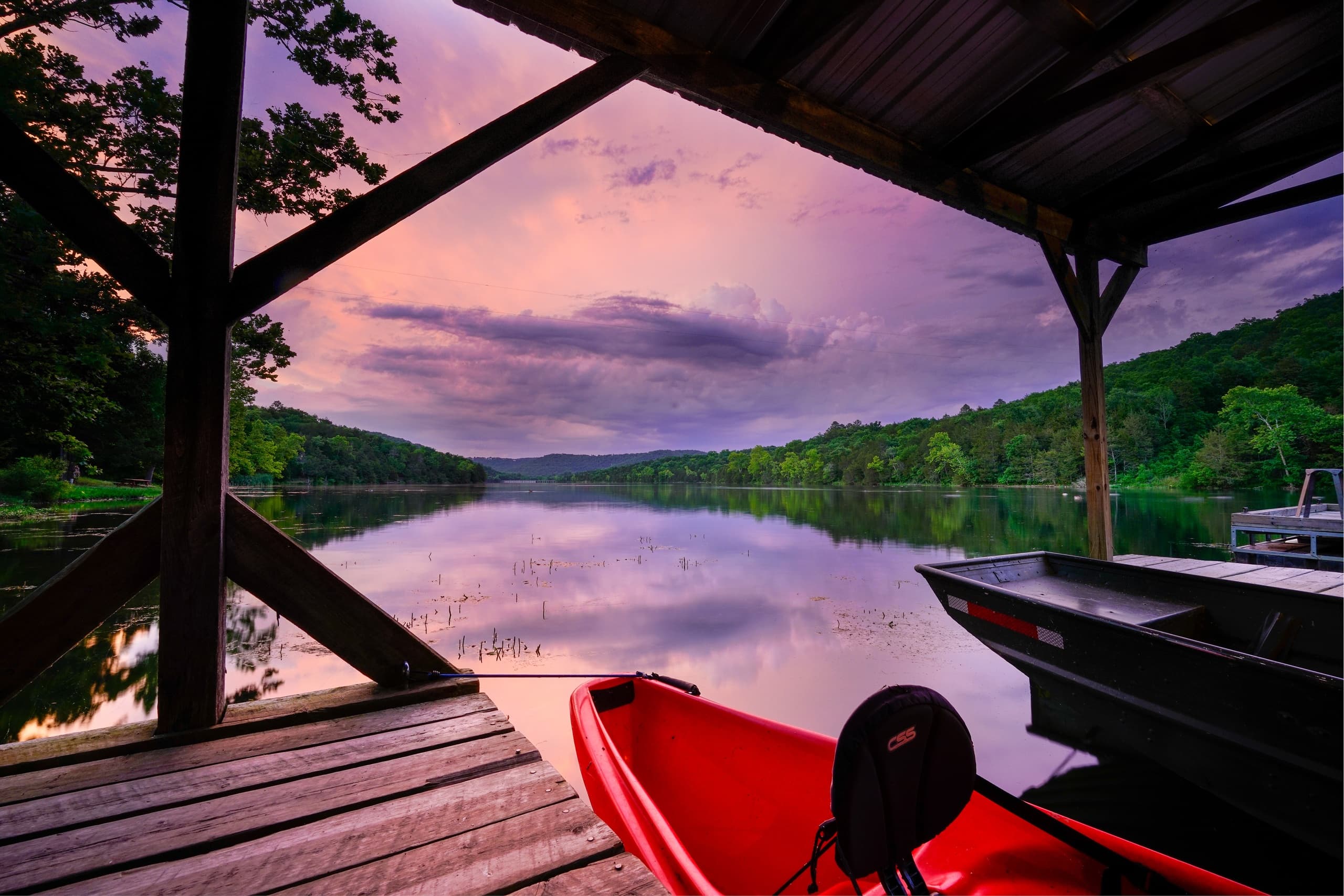 Kayak at lakeside dock at sunset, tranquil water and sky views