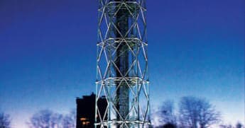 Illuminated observation tower at dusk with trees and skyline