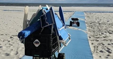Beach equipment cart and folded umbrellas on sandy shore with mat