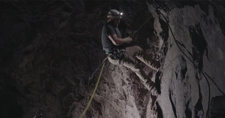 Technical cave rappelling descent on rope in deep limestone cavern