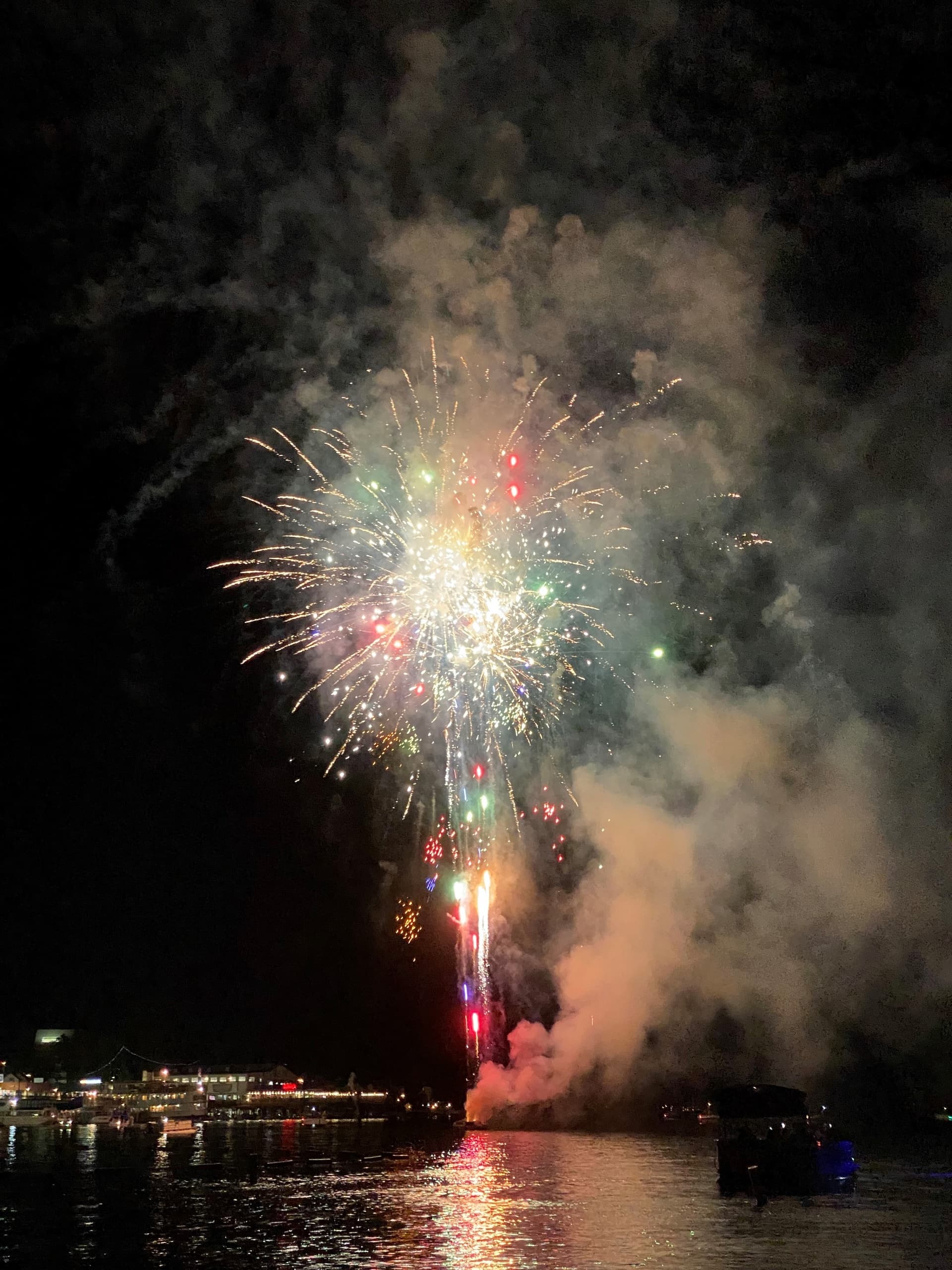 Fireworks exploding over lake during nighttime festival celebration