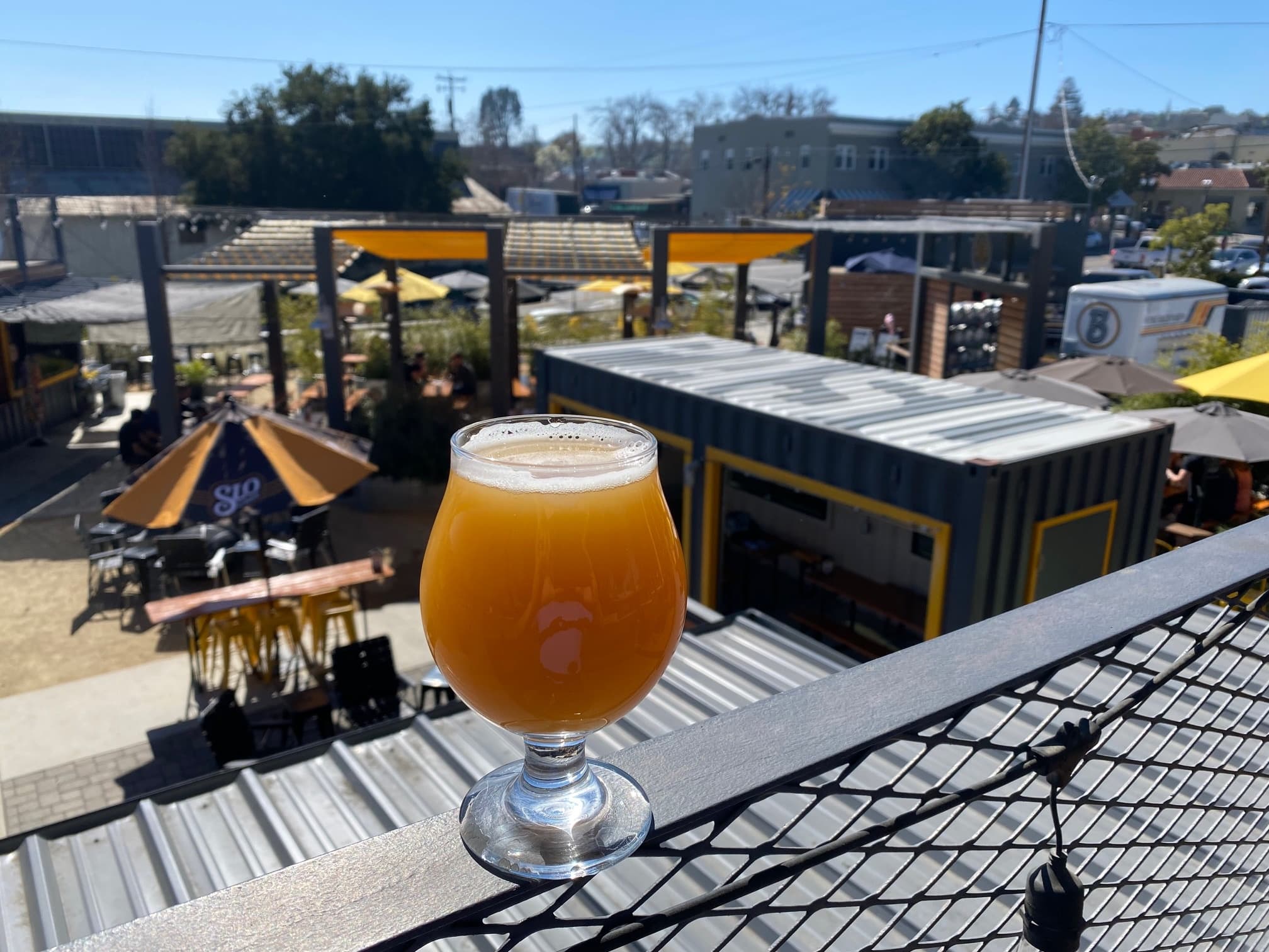 Glass of craft beer on rooftop overlooking outdoor beer patio