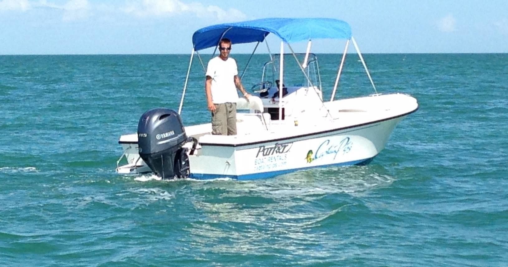 Small rental boat on turquoise open ocean near horizon, coastal