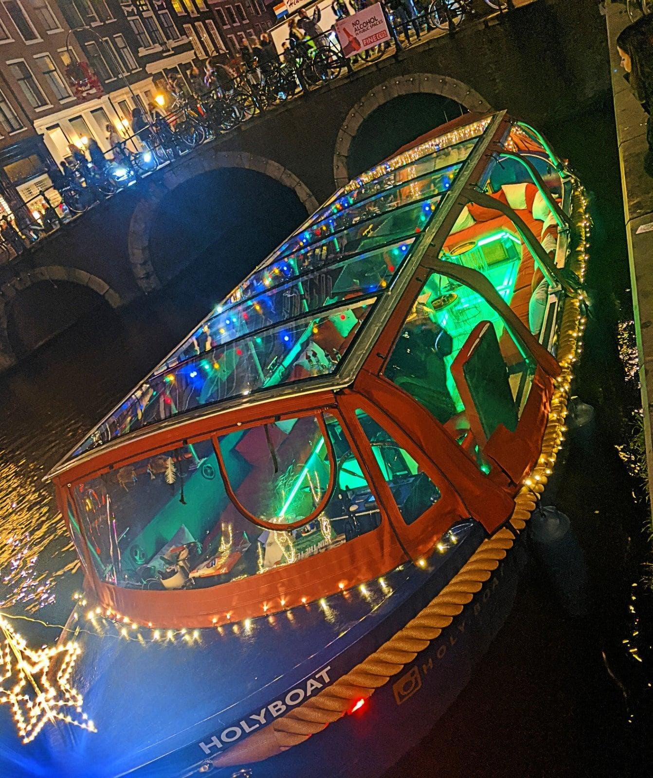 Illuminated glass canal boat lit up during Amsterdam night tour