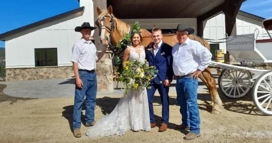 Bride and groom posing with horse and carriage on ranch