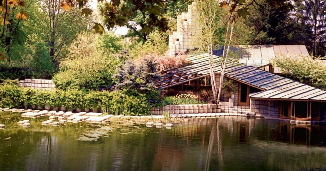 Woodland pond house with low roofline and reflective water view