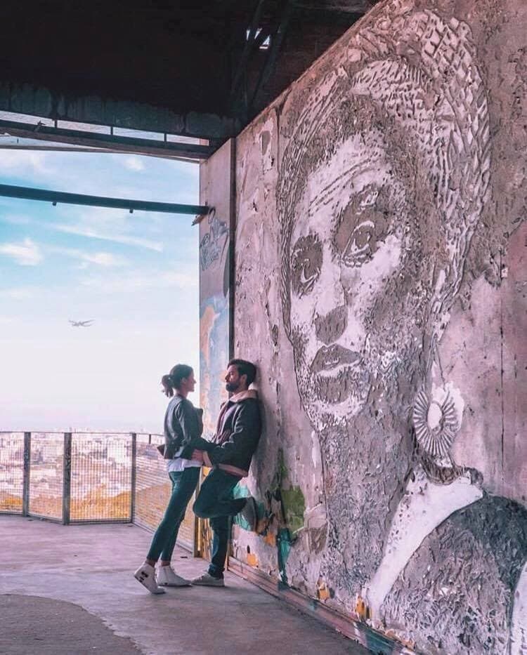 Couple admiring large mural at urban viewpoint overlooking city