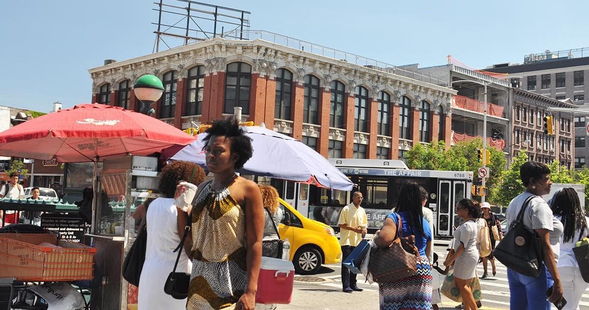 Busy outdoor street market with vendors and summer crowds