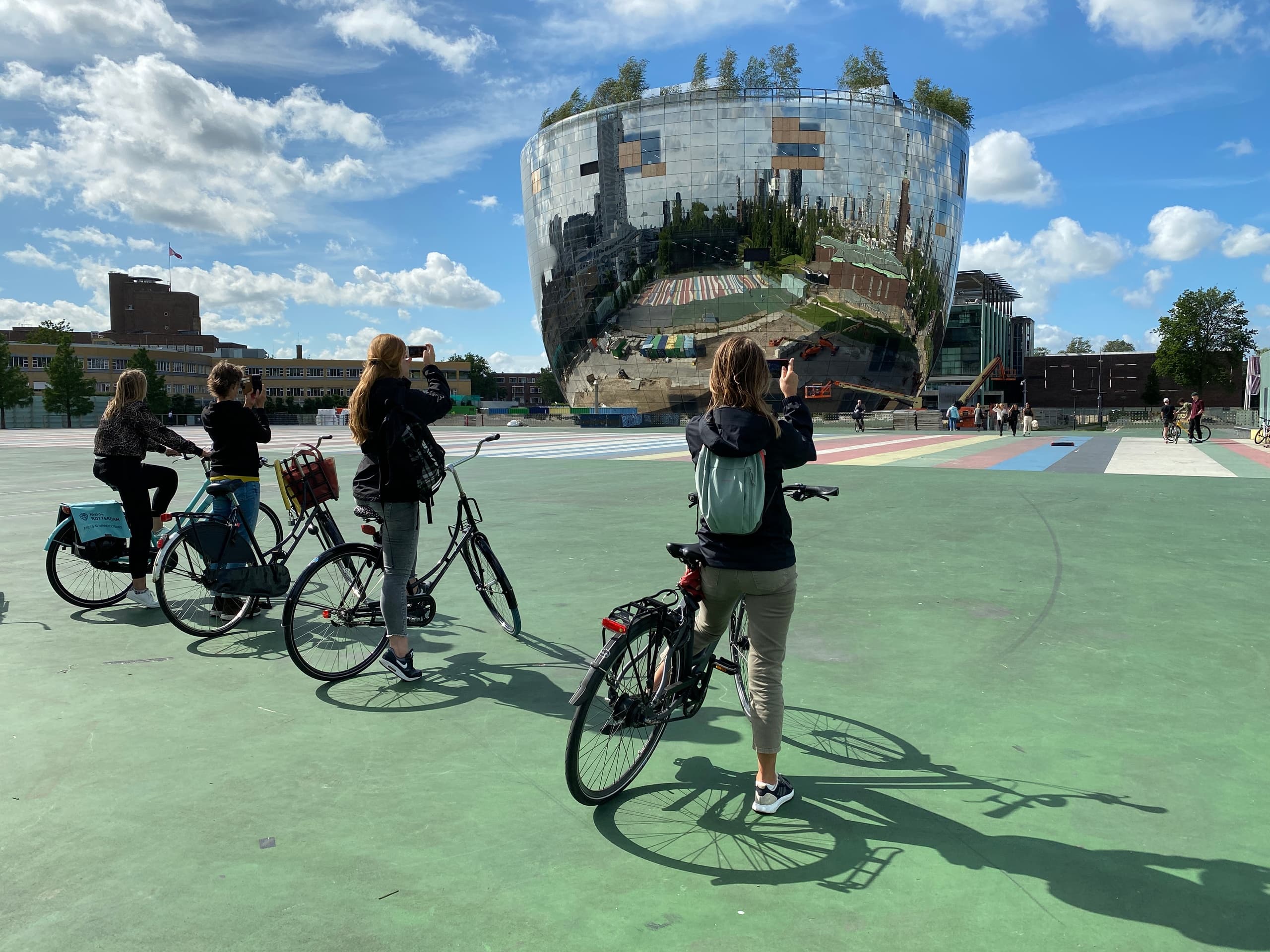 Cyclists near reflective pavilion at Rotterdam waterfront plaza