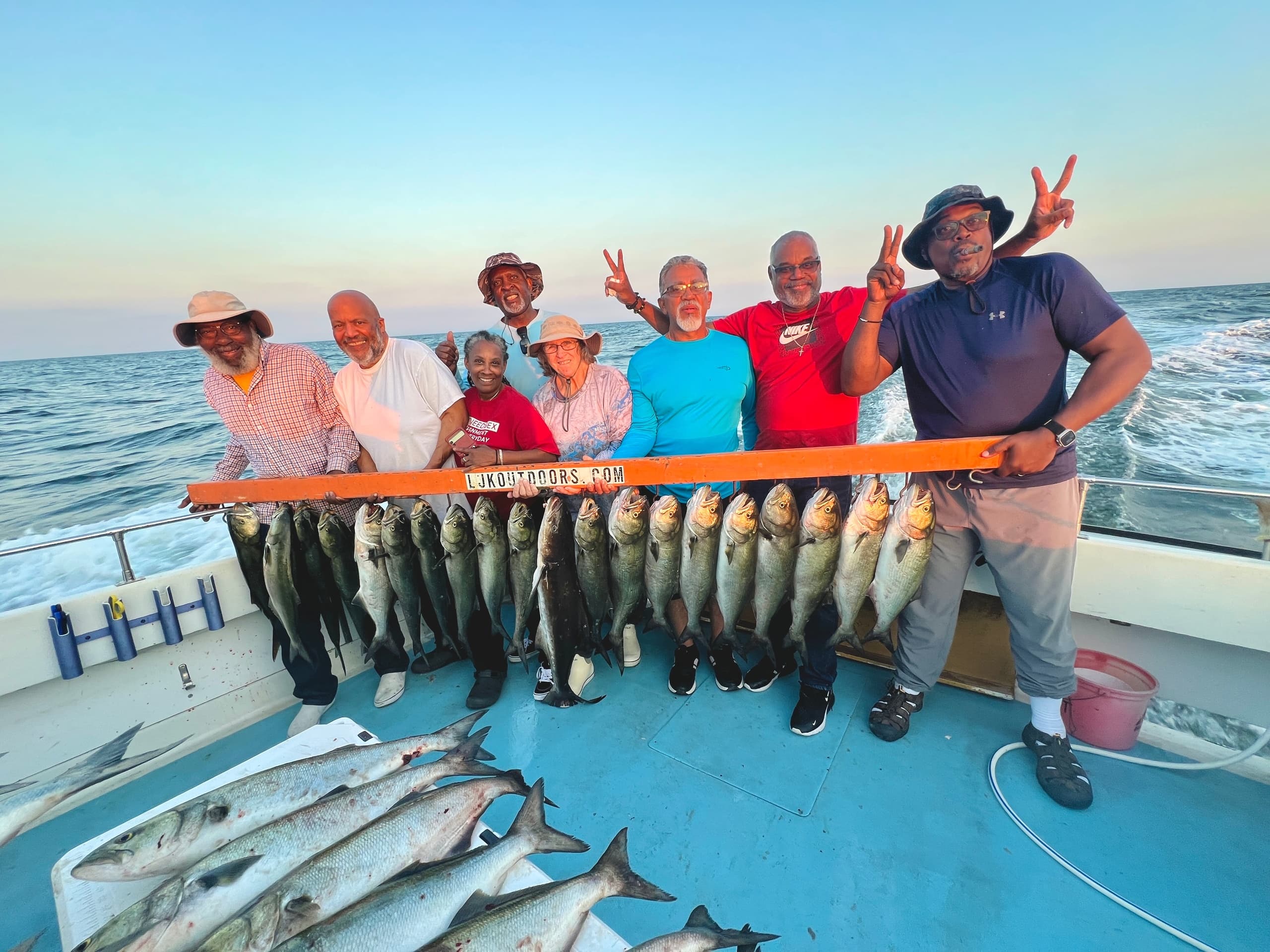 Group of anglers posing with trophy fish aboard a sunset boat