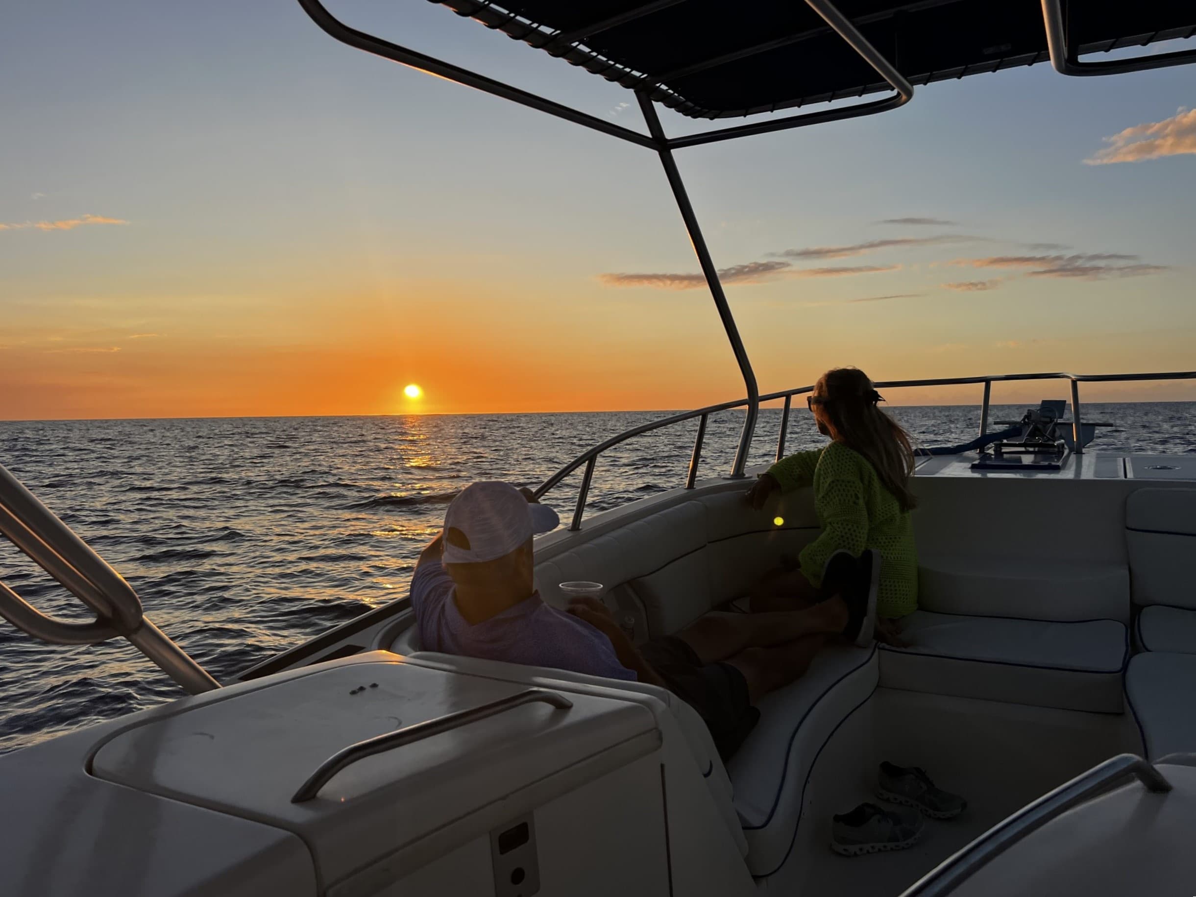 Passengers relaxing on a boat at ocean sunset watching horizon