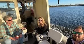 Passengers seated inside small boat cruising along calm river