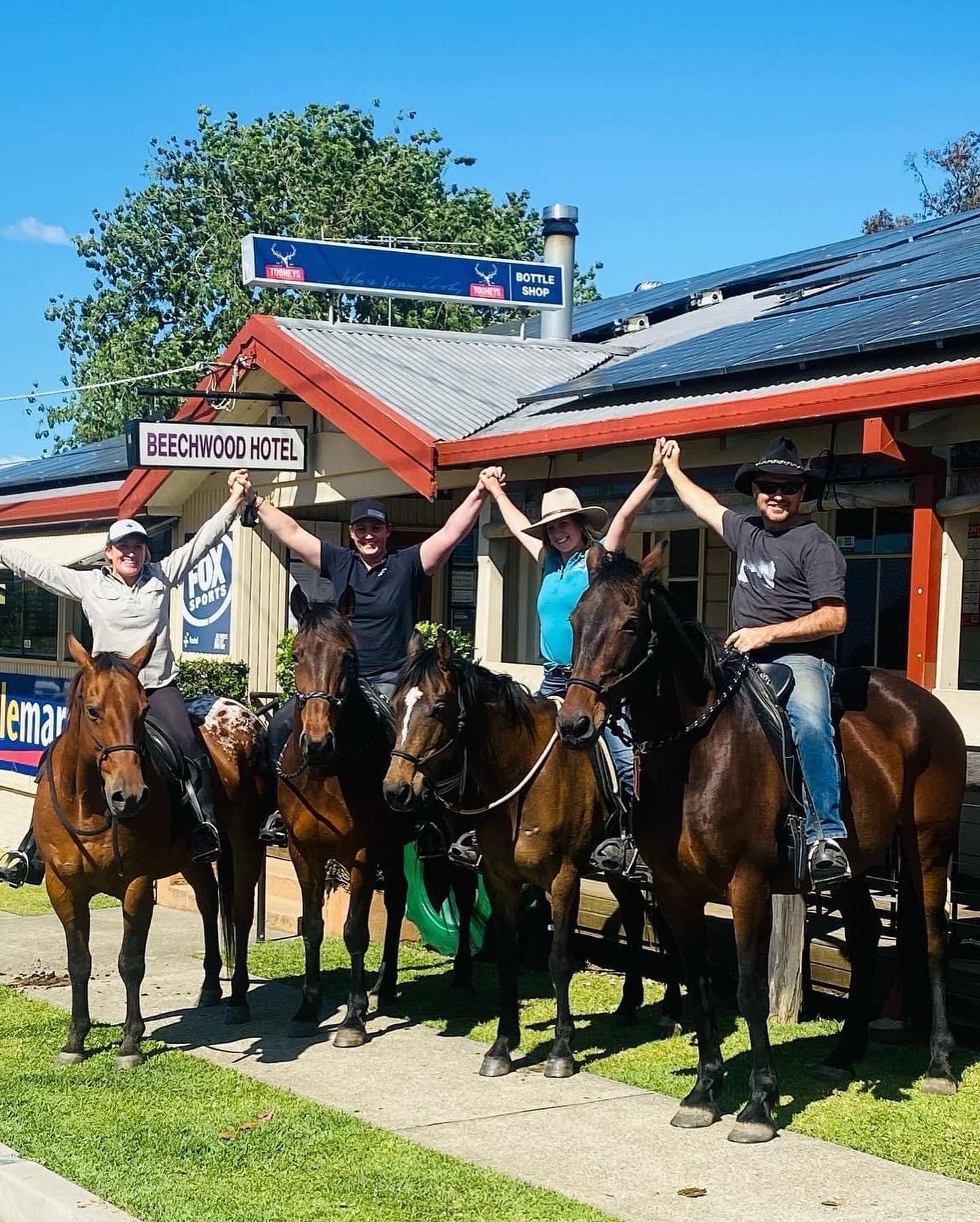 Group horseback riders posing outside country hotel after ride